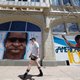 A pedestrian passes murals to honor George Floyd and former NFL quarterback Colin Kaepernick in Denver.